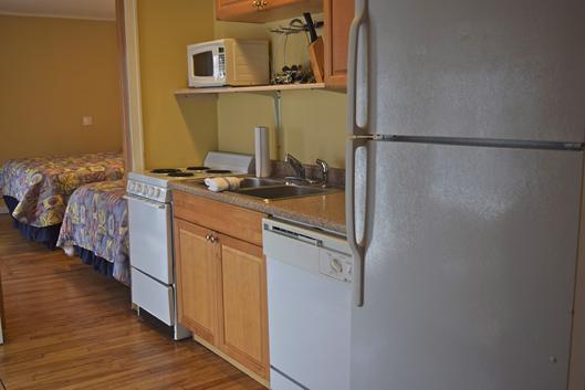 A compact kitchenette area with a bed in the background