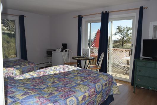 A hotel room with two beds, a TV, and a sliding glass door leading to a balcony.